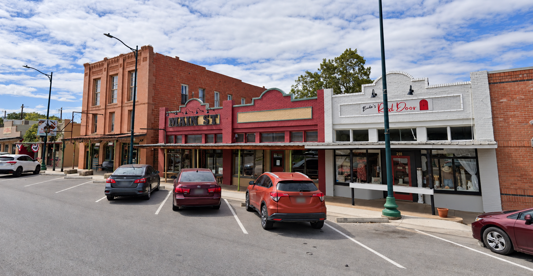 Main Street storefronts in downtown Buda, including the Main St sign and Buda's Red Door.