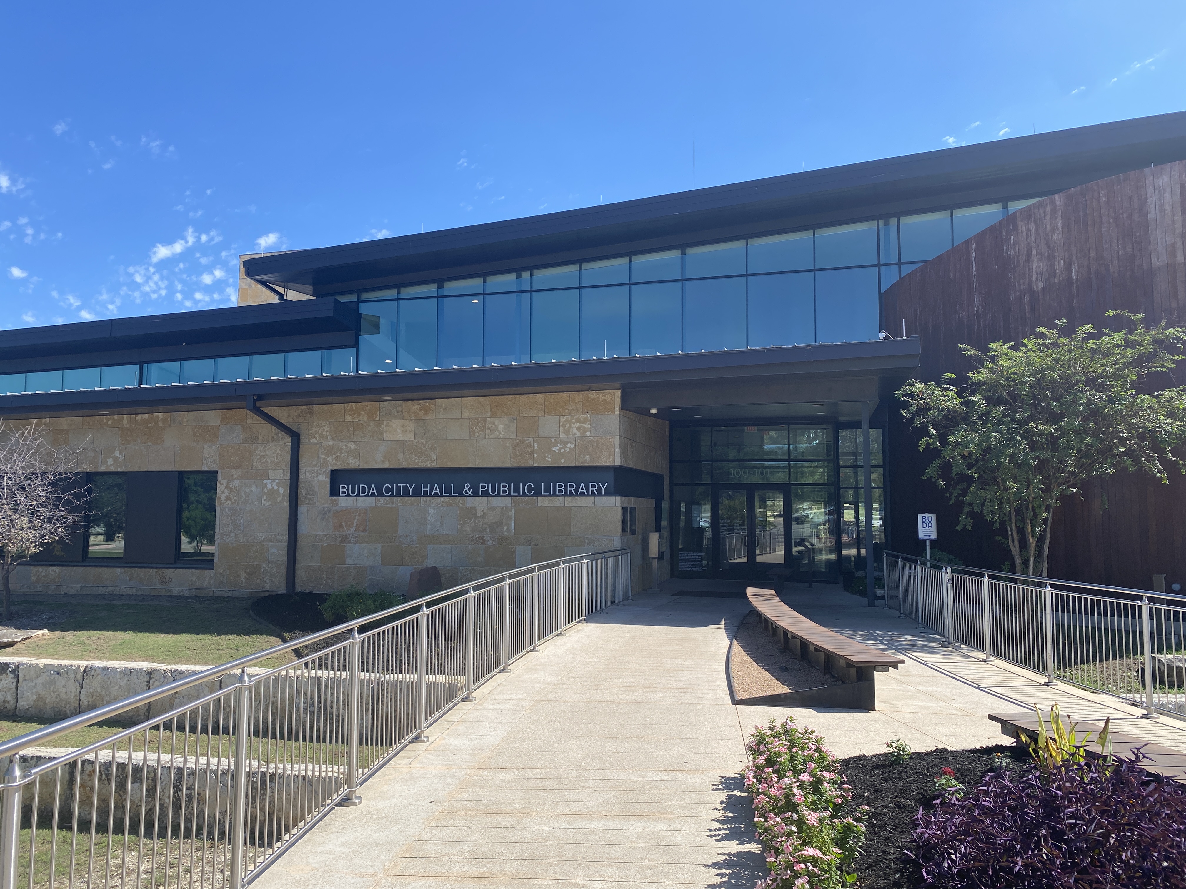 Buda City Hall and Public Library entrance, with its sign, accessible ramp and landscaping.
