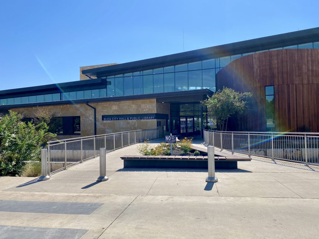 The entrance to Buda City Hall and Public Library, with flowers and accessible walkways.