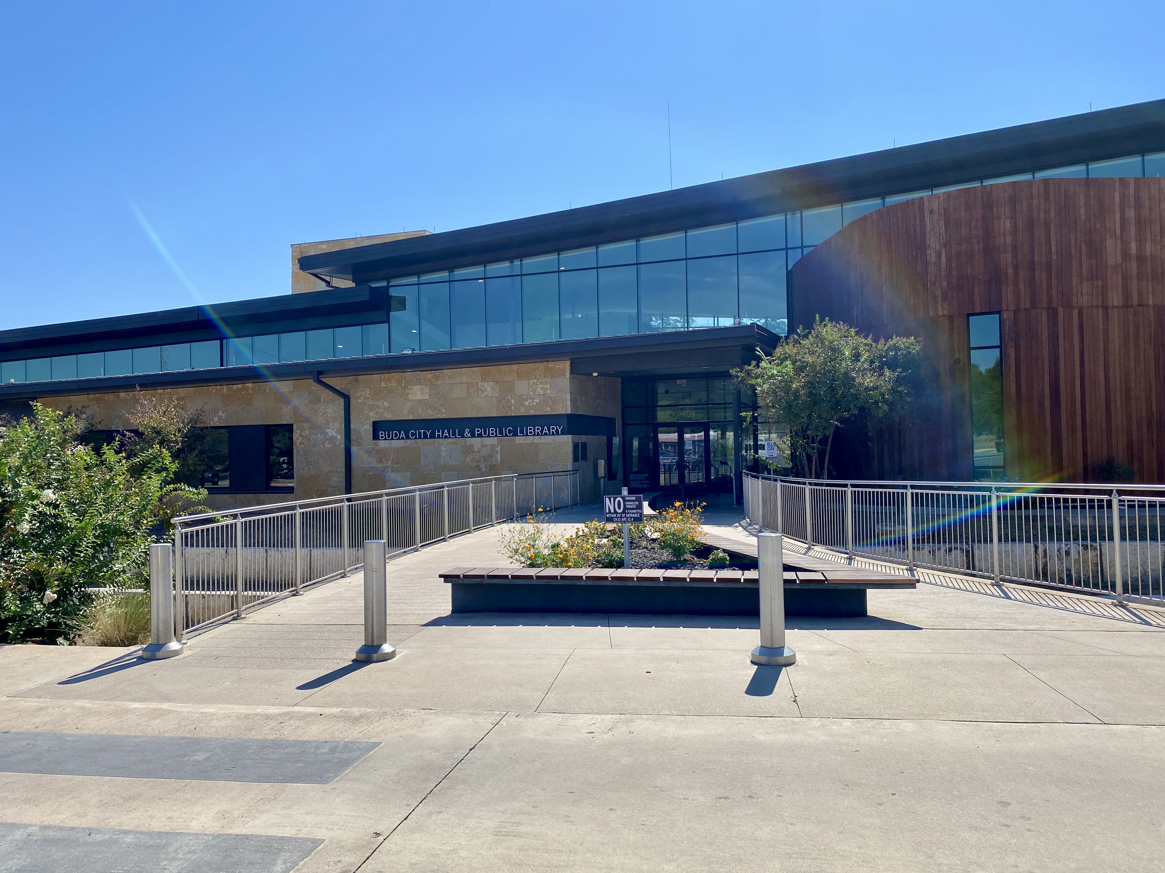 The entrance to Buda City Hall and Public Library, with flowers and accessible walkways.