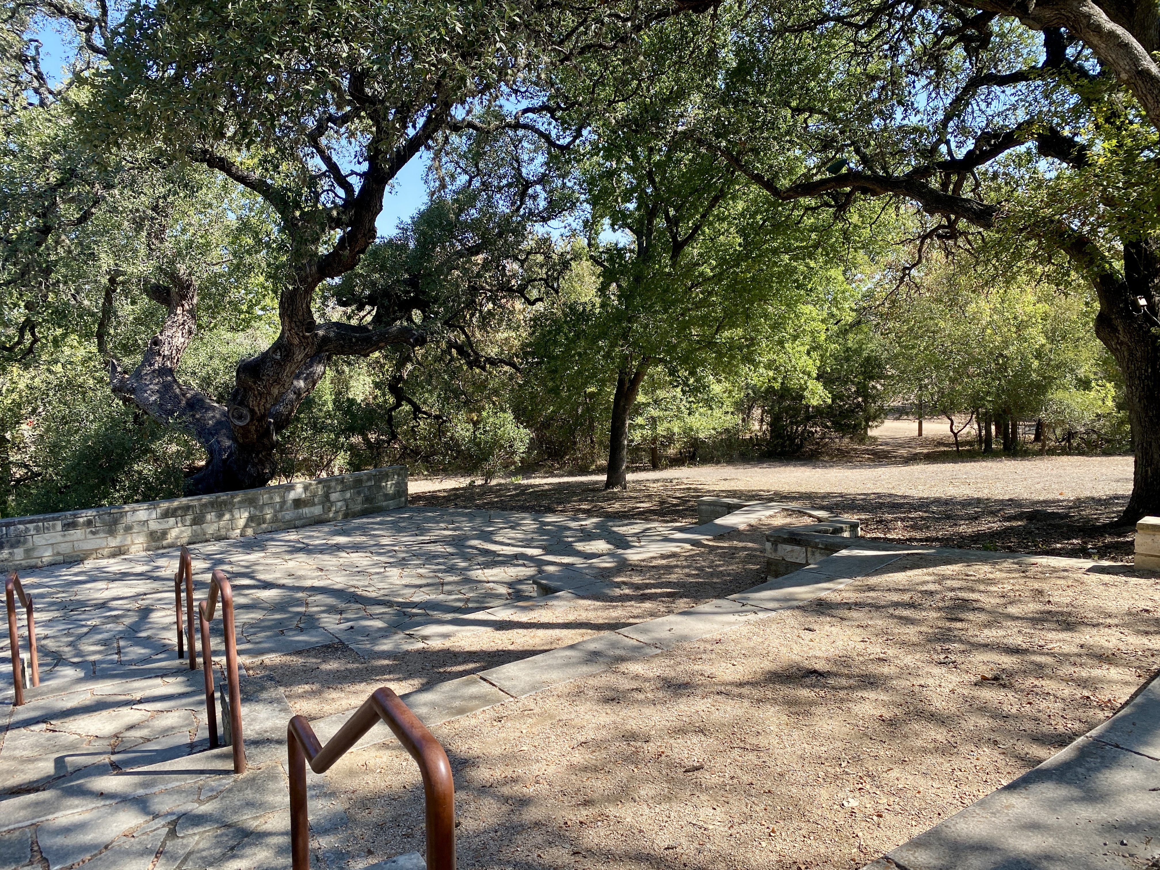 Stone paths and steps wind beneath mature oak trees.