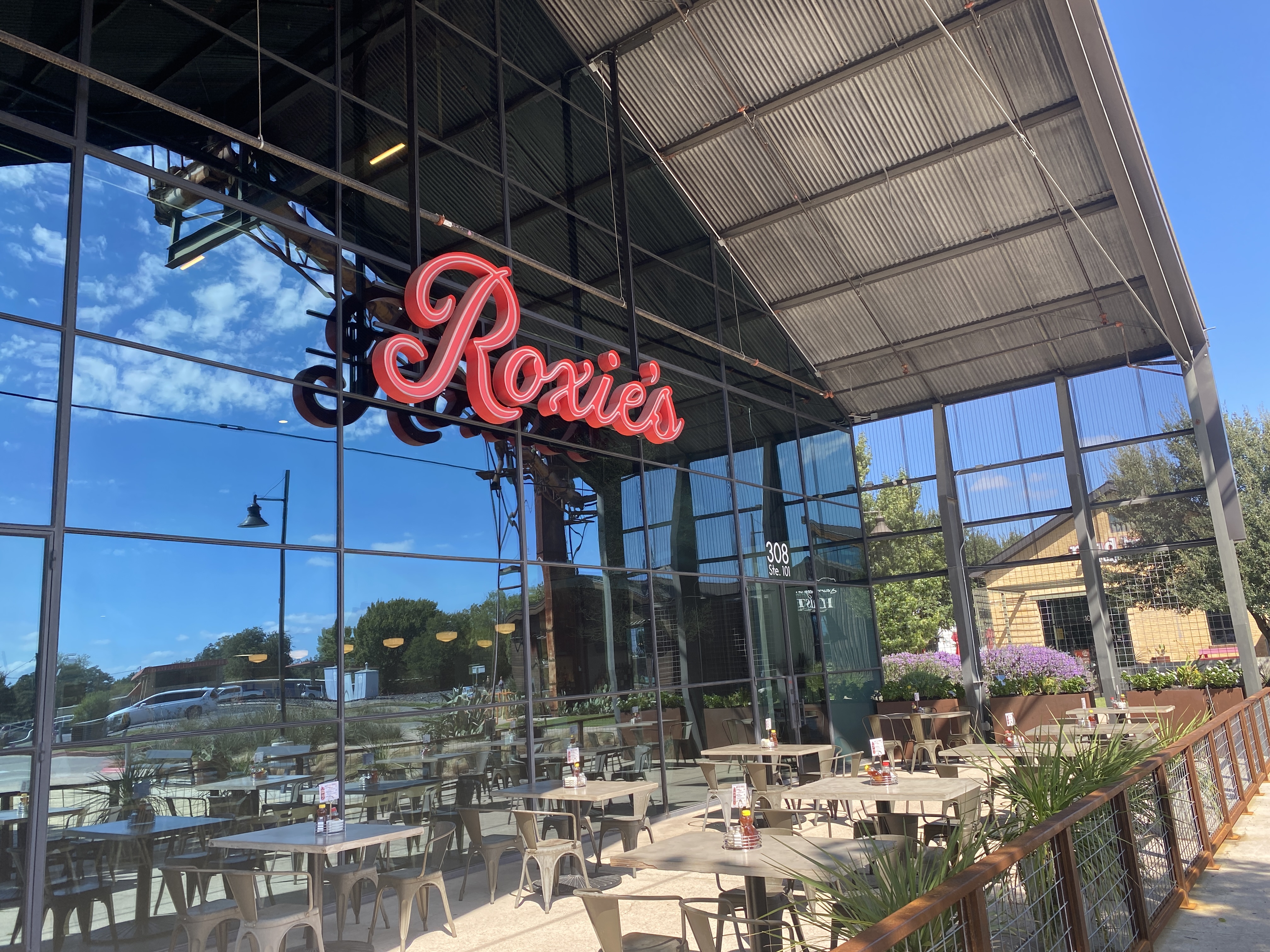 Roxie's red sign above the covered patio and outdoor tables in Buda.